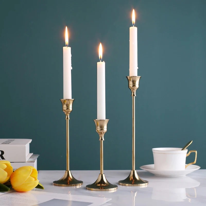 Gold candle holders with lit candles on a coffee table