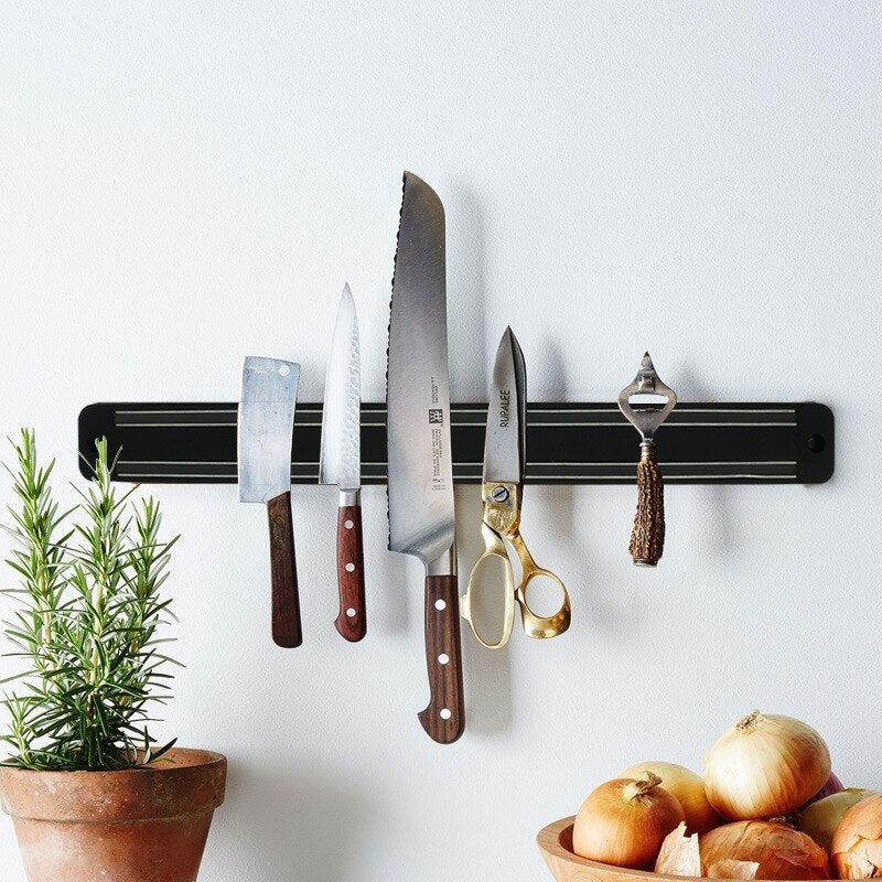 A magnetic knife holder holding knives and metal kitchen tools in order