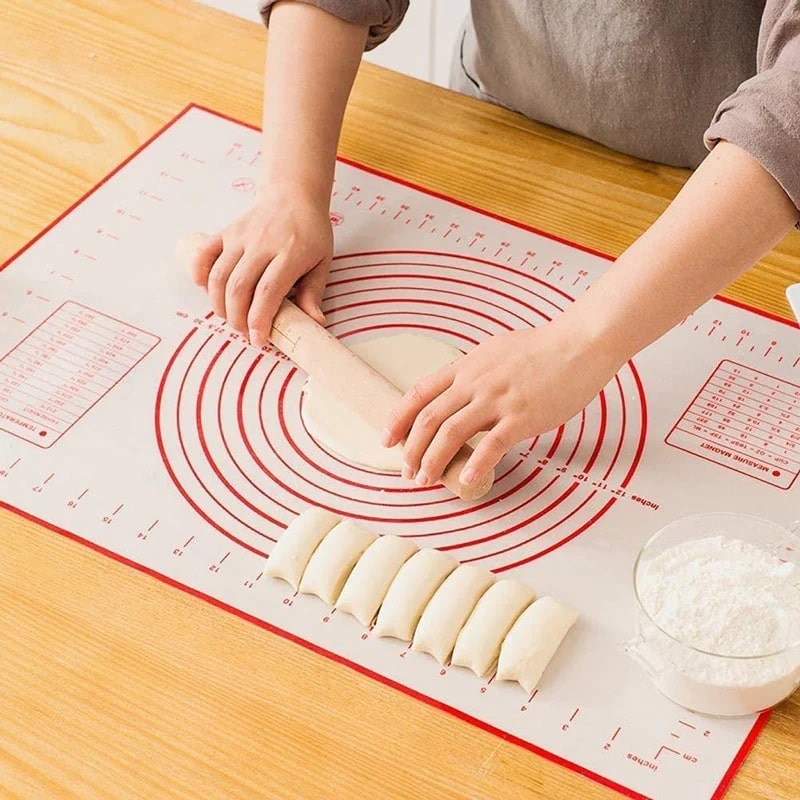 A person effortlessly rolling dough into a perfectly round circle on a versatile silicone countertop mat for precise and easy baking.