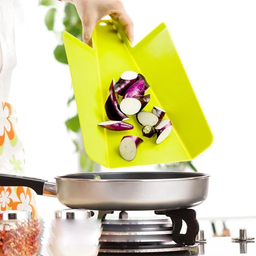 Chopped vegetables falling to the pan from a folded cutting board