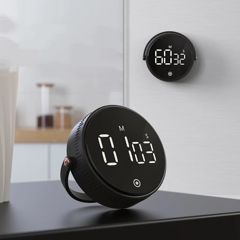 A magnetic kitchen timers hung on the fridge and standing on the table