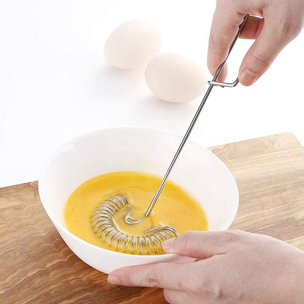 Coil whisk beating eggs in a bowl