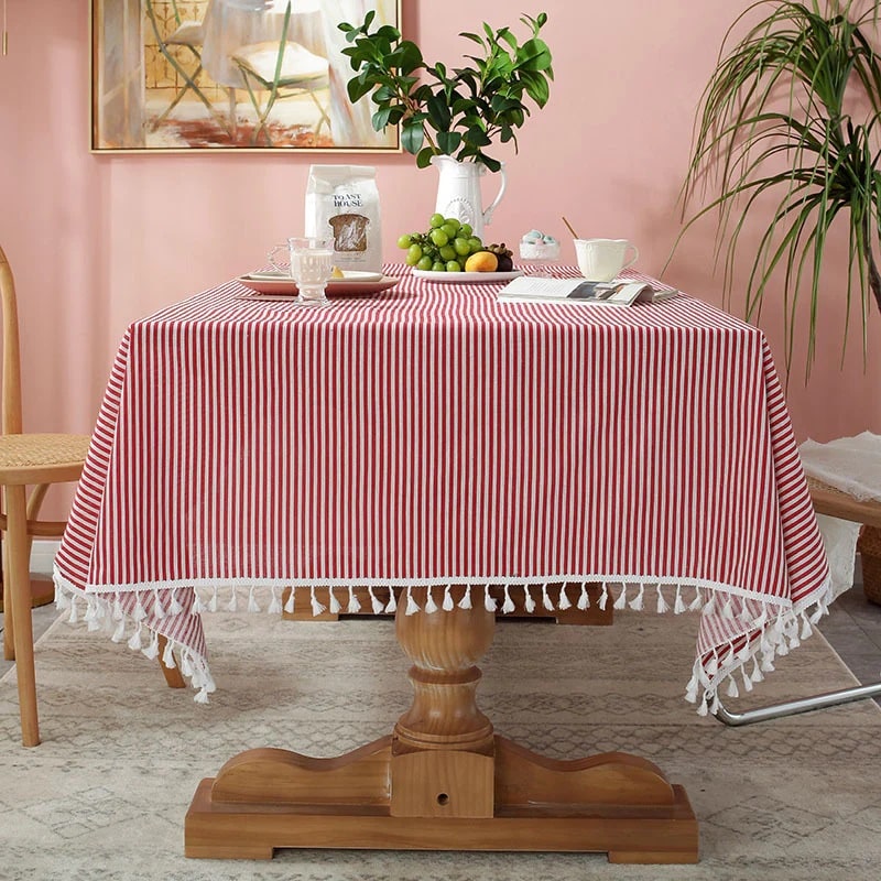 A cozy tea table set with a red and white striped tablecloth and tassels encircling the cloth.