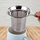 A metal tea strainer basket ready to dive into the tea mug