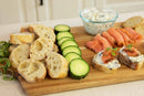 A good looking cutting board used as a tray with slices bread and delicious toppings