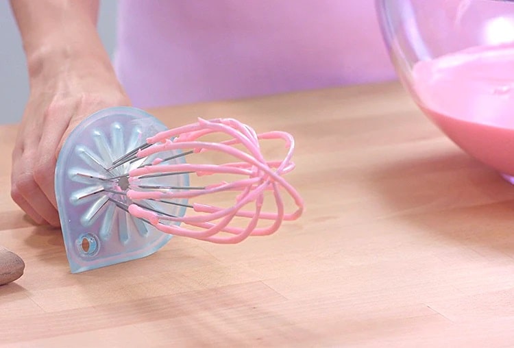 A balloon whisk resting on the counter making no mess when whisk cleaner is attached to it